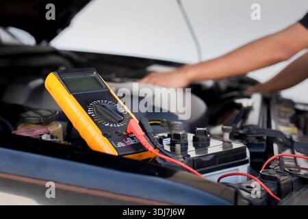 Auto mechanics use voltmeters to check battery voltage. Stock Photo