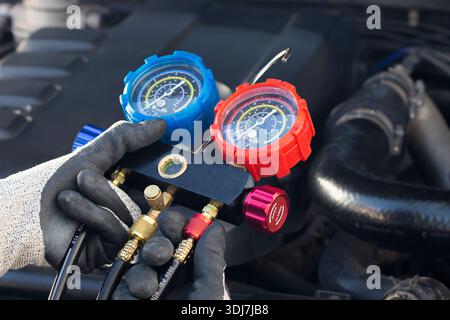 Car air conditioning technician, checks refrigerant and refills air conditioning fluid, car air conditioning service Stock Photo