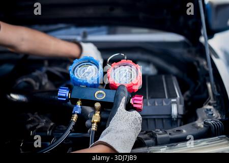 Car air conditioning technician, checks refrigerant and refills air conditioning fluid, car air conditioning service Stock Photo