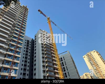 Construction of high-rise residential buildings with a crane against a clear blue sky Stock Photo