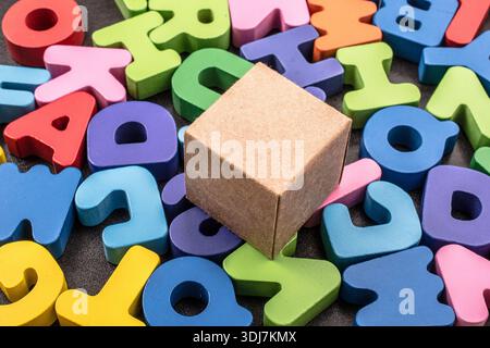 Cardboard box cube and Colorful Letters of Alphabet Stock Photo