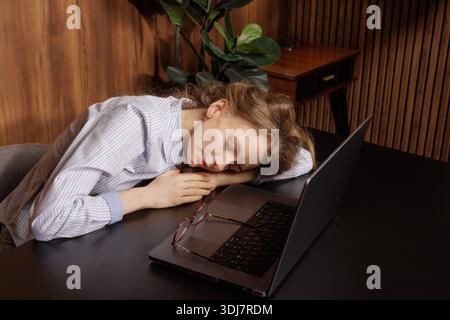Exhausted woman asleep at work, burnout and fatigue from remote job, overworked employee resting. Stock Photo