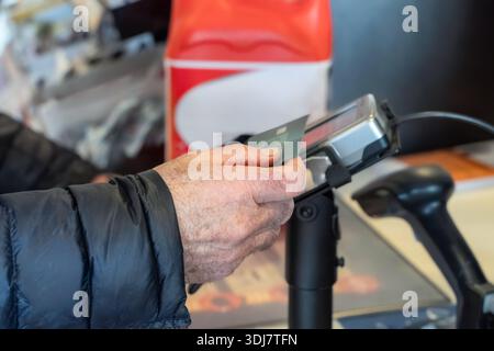 Adult male is using a credit card at a payment terminal in a retail setting, demonstrating the convenience of modern transactions and customer service Stock Photo