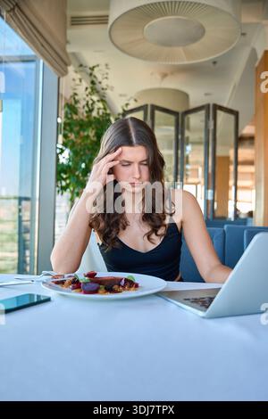 Young woman using laptop while sitting in the restaurant Stock Photo