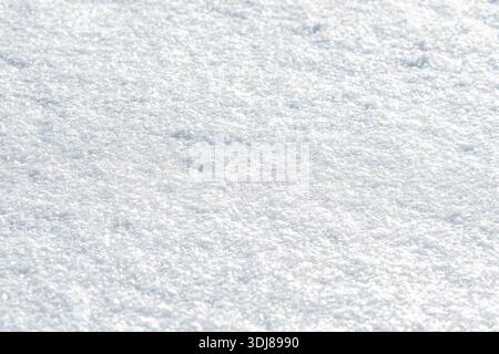 A close-up view of sparkling snow crystals, softly illuminated by sunlight, creating a bright, textured winter background with a serene and minimalist Stock Photo