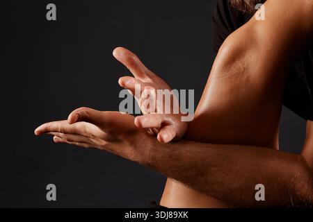 handsome male masseur doing a massage on a girl's leg on a black background, concept of therapeutic relaxing massage. Stock Photo