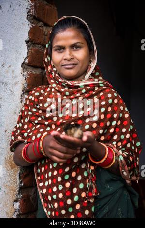 Portrait of a young woman from rural Odisha holding a small chick, India Stock Photo