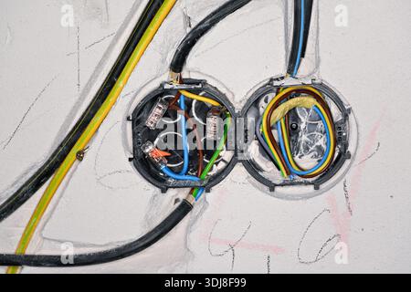 Boxes with cables for electric sockets installed in new house building empty wall Stock Photo
