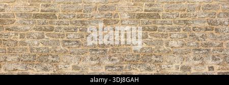 Rough gray stone wall texture forming weathered masonry with mortar joints Stock Photo