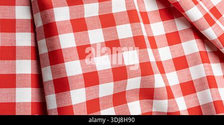 Gingham fabric featuring a classic red and white checkered pattern creating natural folds Stock Photo
