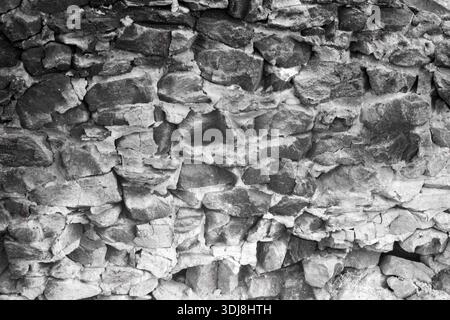 Rustic rubble masonry wall with irregular, rough-hewn stones of various sizes, bound by visible mortar, creating a textured, aged surface. Stock Photo