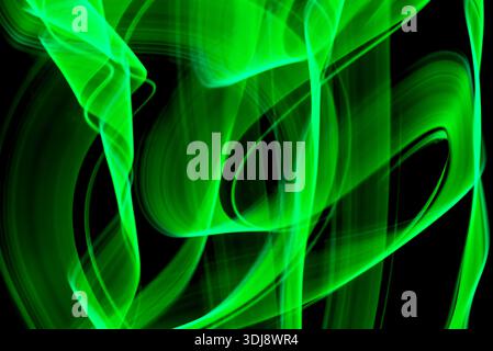 Smooth green energy smoke waves forming calm abstract motion with luminous glow on black background. Stock Photo