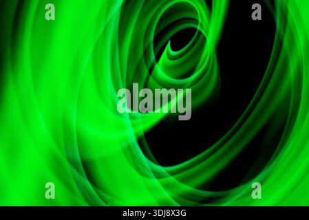 Circular green energy vortex forming hypnotic abstract motion with luminous glow on dark background. Stock Photo