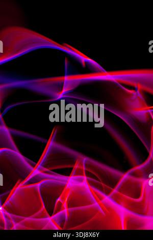 Vertical flowing pink and purple energy lines creating vivid abstract luminous motion. Stock Photo