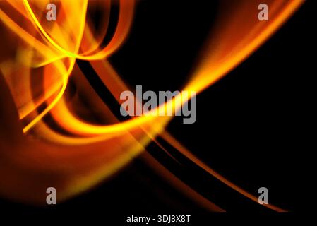 Flowing orange fire light creating energetic abstract motion with glowing highlights on dark background. Stock Photo