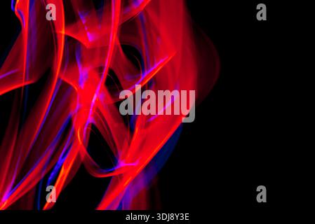 Flowing pink and red luminous lines creating elegant abstract energy movement on dark background. Stock Photo