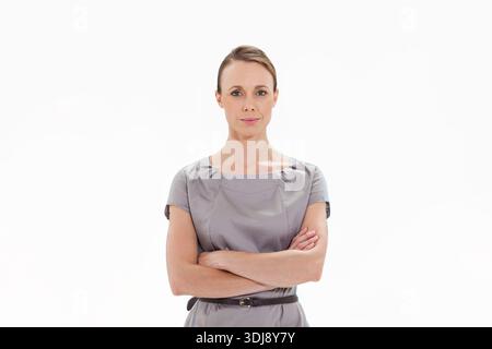 Mid-adult woman posing in studio, wearing grey short-sleeve dress with thin dark belt. Female, corporate, portrait, minimalist, highkey, neutral, pois Stock Photo