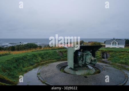 View of an old cannon from World War II on a bunker in the small Norwegian coastal town of Bud in rainy weather. Stock Photo