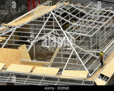 A worker with a safety harness installing wooden panels on a steel roof construction. Occupational safety and working at heights techniques.Sariyer, ï¿½ Stock Photo