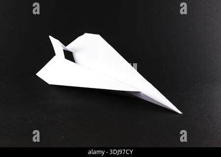 Solitary white paper airplane in flight on a black background Stock ...