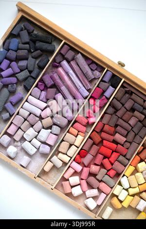 Soft pastels set in wooden box on white table. Drawing material. Art background. Open wooden box of soft pastels top view, multicolor art supplies. Ve Stock Photo