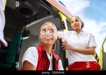 Two female nurses by the ambulance. Two paramedics by the ambulance, smiling. Stock Photo