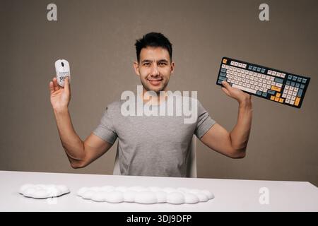 Portrait of smiling man presenting ergonomic computer peripherals and wrist rests for improved comfort and productivity, holding white mouse and Stock Photo