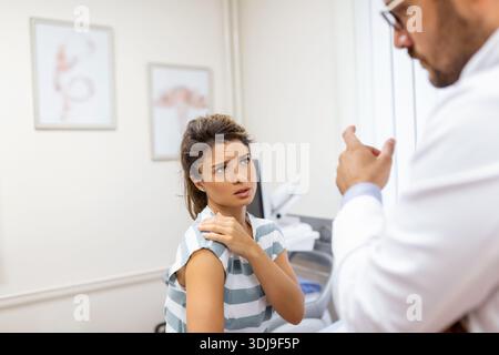 Woman having a shoulder pain. Doctor working in the office and listening to the patient, she is explaining her symptoms, healtcare and assistance conc Stock Photo