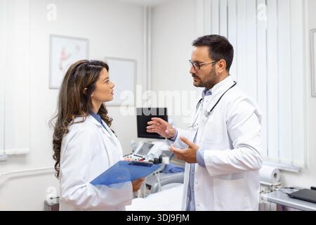 Team of doctors working together on patients file at hospital. Medical staff analyzing report and working at clinic. Woman doctor having discussion in Stock Photo