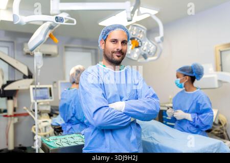 Portrait of male surgeon standing with arms crossed in operation theater at hospital. Team surgeons are performing an operation, middle aged doctor is Stock Photo