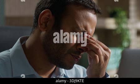Tired Indian business man rubbing eyes looking at laptop indoora office businessman removing glasses male online computer monitor eyestrain headache Stock Photo