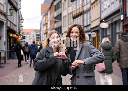 Two happy women making heart shape gesture Stock Photo