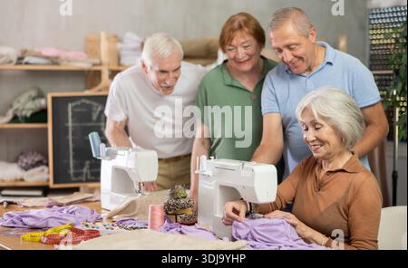 Retired students learning sewing from female instructor in tailoring workshop Stock Photo