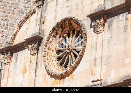 Intricate stone carving of large, wheel-shaped rose window on facade of St. Saviour Church in Dubrovnik, Croatia. Renaissance architectural detail is Stock Photo