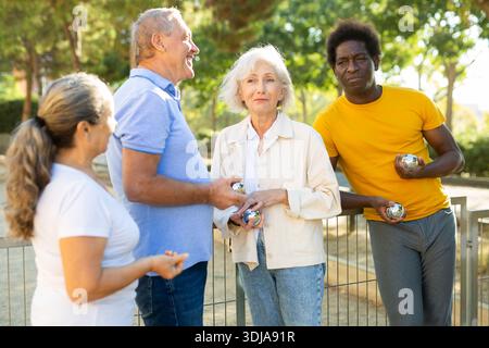 Two adult couples share their impressions after playing petanque Stock Photo