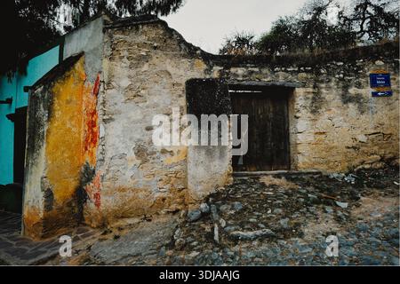 An old stone wall with vibrant murals on a rustic alleyway, offering a glimpse into the charm of historic architecture Stock Photo