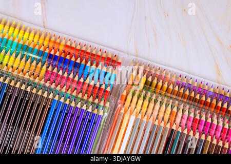 Colored pencils are organized case on light surface with many shades hues visible in different sections. Stock Photo