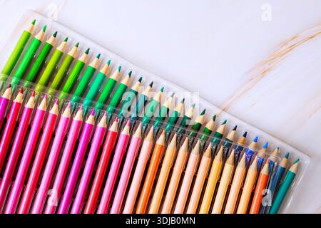 Set of colored pencils with various colors is neatly arranged in plastic case on flat surface. Stock Photo