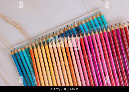Collection of drawing pencils shows different colors in clear case on plain surface. Stock Photo