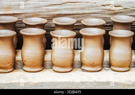 Handcrafted clay vessels positioned in symmetrical rows during the drying phase, capturing the precision of artisanal pottery work Stock Photo
