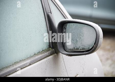 The side mirror of a car is completely covered in frost, showing the effects of freezing temperatures Stock Photo
