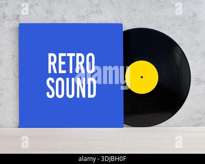 Black vinyl record with yellow label and blue cover leaning on concrete wall, evoking retro music and vintage sound Stock Photo
