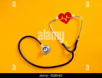 Medical stethoscope embracing red heartbeat shape over yellow background representing healthcare and cardiology Stock Photo