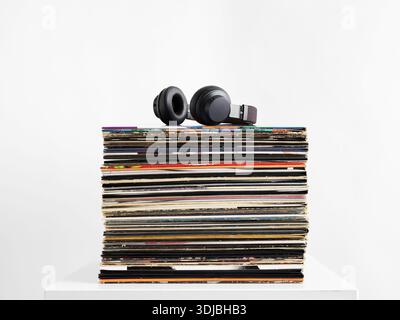 Stack of vinyl records topped with black headphones, symbolizing music appreciation and the timeless appeal of analog sound Stock Photo