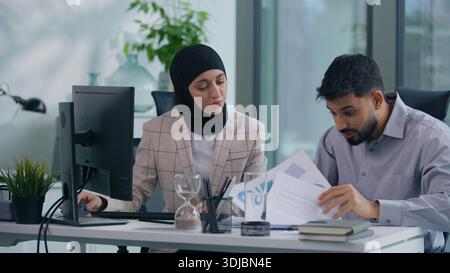 Two muslim business team in office working Islamic group Indian co-workers Arabian colleagues discuss problem bad data information problem difficulty Stock Photo
