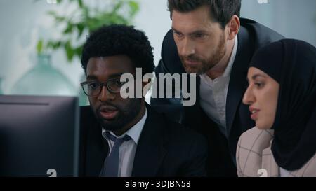 Diverse business team in modern office discussing project looking at computer screen multiethnic teamwork collaboration Muslim woman in hijab with Stock Photo