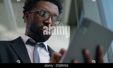 Happy African American businessman in office smiling using digital tablet modern technology business man smiling success professional male manager Stock Photo