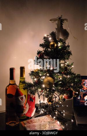 Cozy indoor Christmas scene with a decorated tree, warm string lights, and festive holiday decorations on a tabletop. Stock Photo