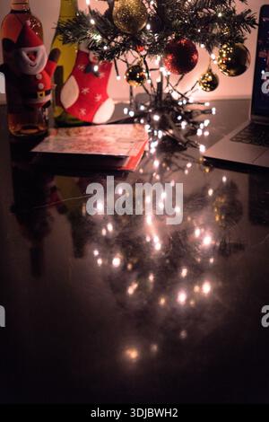 Cozy indoor Christmas scene with a decorated tree, warm string lights, and festive holiday decorations on a tabletop. Stock Photo