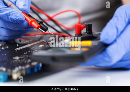 Technician under fixed and repairing computer mainboard process by used multimeter AC Voltage for analysis on computer mainboard is electronic compone Stock Photo